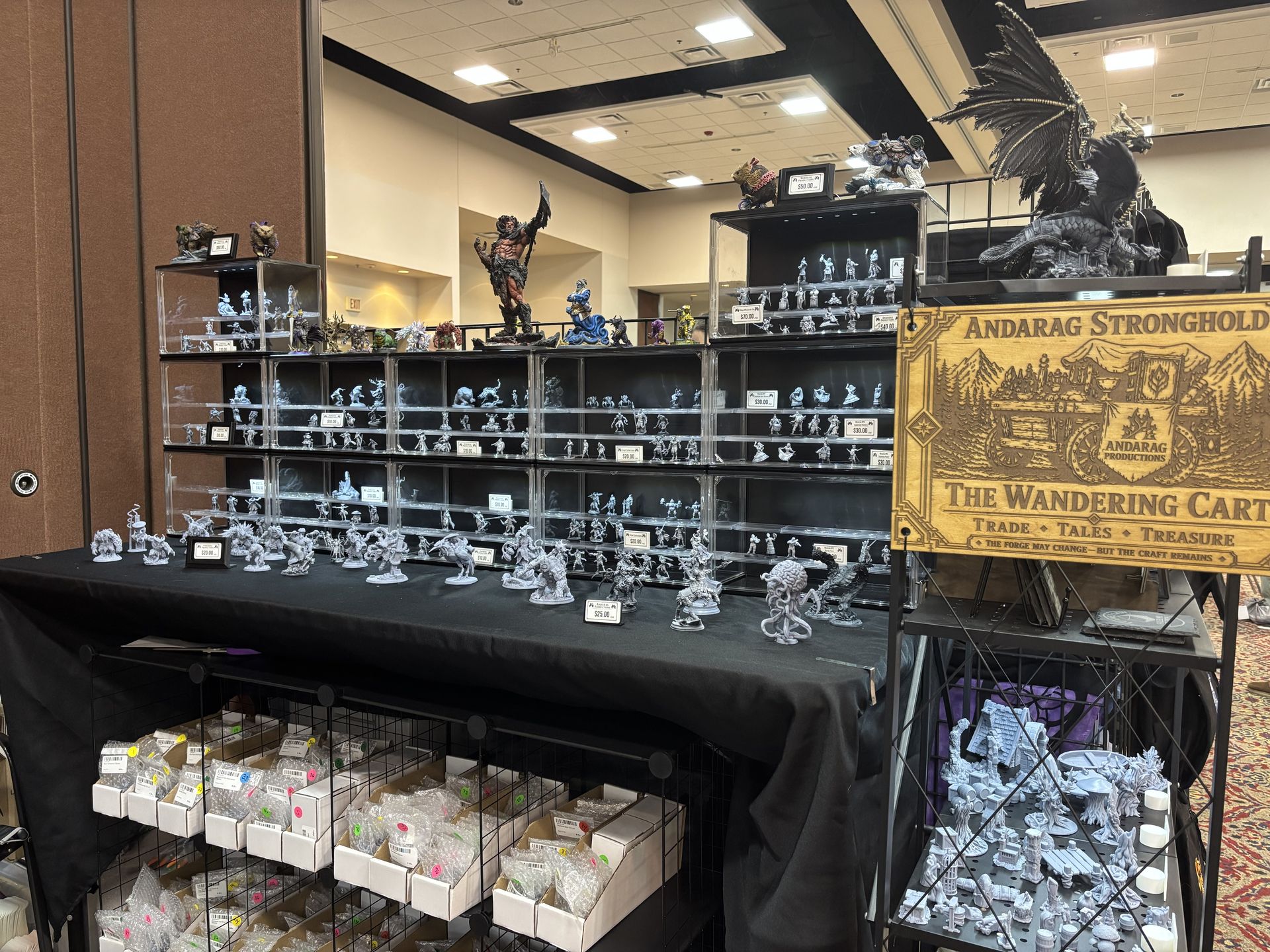 Andarag Productions vendor booth at DieCon with shelves of resin miniatures and handcrafted gaming items.