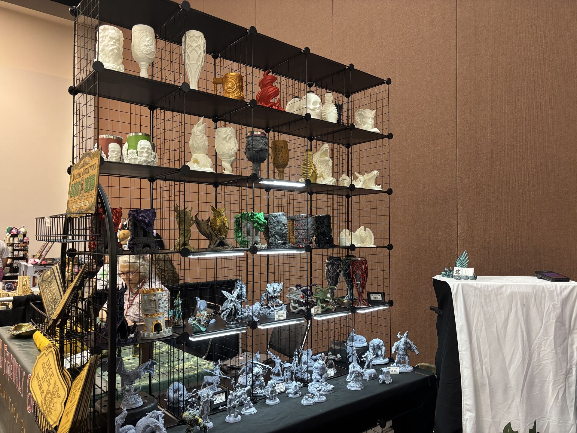 Andarag Productions booth display at DieCon featuring tabletop miniatures, terrain, and gaming accessories.